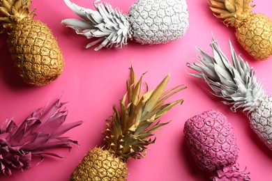 Photo of Different painted pineapples on pink background, above view. Creative concept