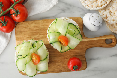 Puffed rice cakes with vegetables served on white marble table, flat lay