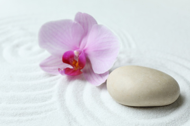 Stone and beautiful flower on sand with pattern. Zen, meditation, harmony