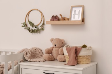 Wooden shelf with baby accessories and toys in child room. Interior design