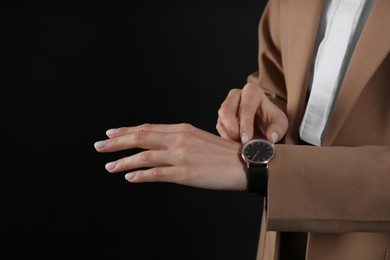 Businesswoman with wristwatch on black background, closeup. Time management