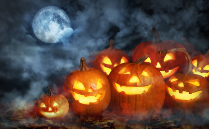 Image of Scary Jack O Lantern pumpkins surrounded by mystical mist under full moon on Halloween