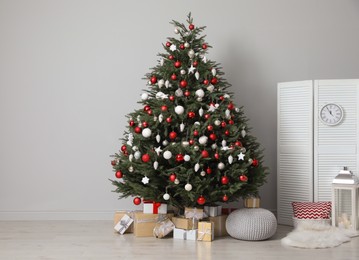 Beautifully decorated Christmas tree and many gift boxes in room, space for text