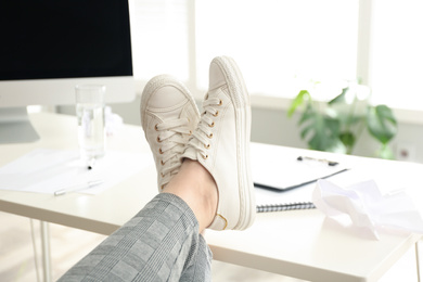 Lazy overweight worker with feet on desk in office, closeup