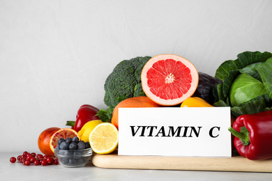 Paper note with phrase VITAMIN C and fresh products on light table