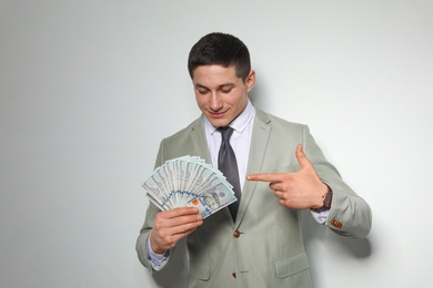 Portrait of young businessman with money fan on light background