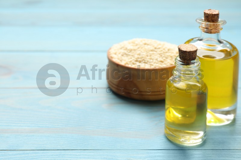Fresh sesame oil and seeds on light blue wooden table. Space for text