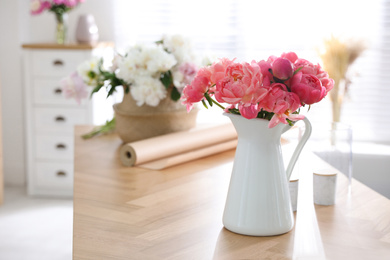 Beautiful bouquet of fragrant peonies in vase on table indoors