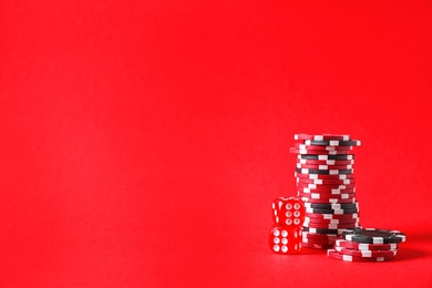 Poker chips and dices on red background, space for text