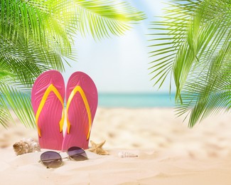 Pink flip flops, starfish, sea shell and sunglasses on sandy beach near sea 