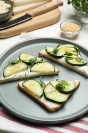 Photo of Tasty cucumber sandwiches with sesame seeds and pea microgreens on white table