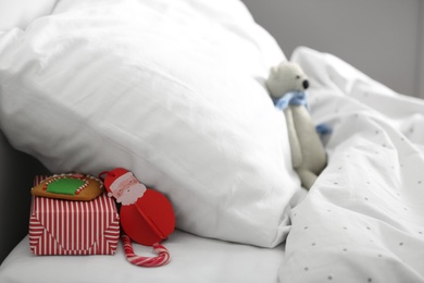 Gift box with candy cane and gingerbread under pillow in children's bedroom. St. Nicholas Day tradition