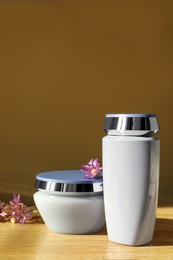 Hair care cosmetic products and beautiful flowers on wooden table
