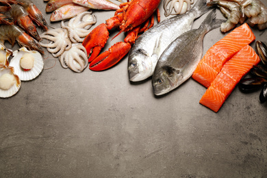Fresh fish and seafood on grey table, flat lay. Space for text