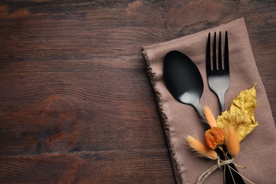 Seasonal table setting on wooden background, space for text. Cutlery with autumn decorations, top view