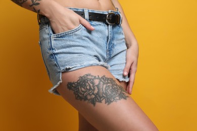Woman with tattoos on body against yellow background, closeup