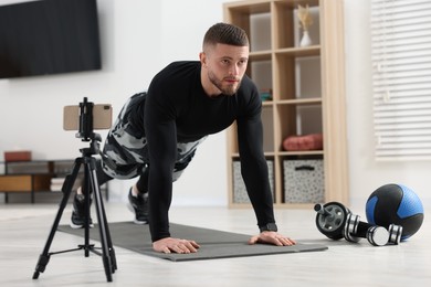 Photo of Trainer streaming online workout with phone at home