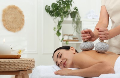 Young woman receiving herbal bag massage in spa salon