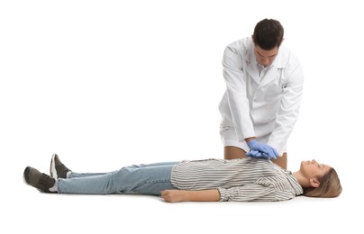 Doctor in uniform practicing first aid on woman against white background