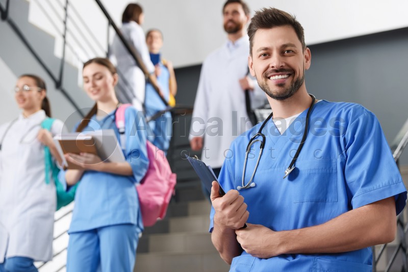 Portrait of medical student with clipboard on staircase in college, space for text