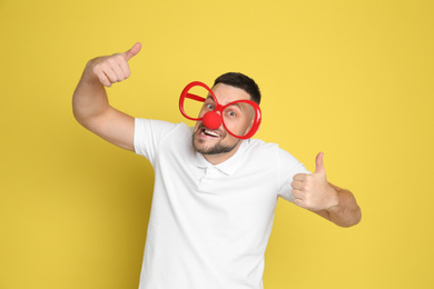 Funny man with clown nose and large glasses on yellow background. April fool's day