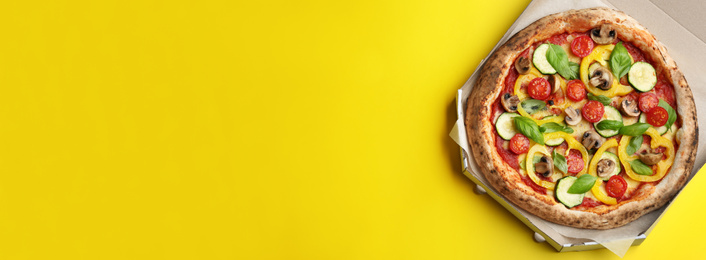 Image of Top view of hot delicious pizza on yellow background, space for text. Banner design 