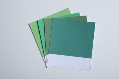Photo of Color sample cards of green shades on light background, top view