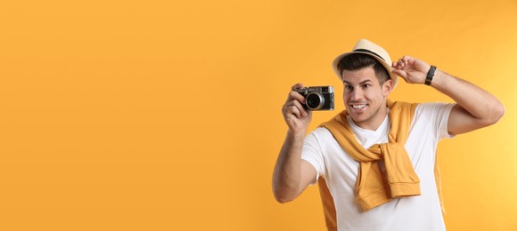 Male tourist taking picture on yellow background