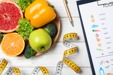Fruits, vegetables, measuring tape and list of products on white wooden background, flat lay. Visiting nutritionist