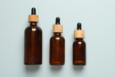 Bottles of face serum on light grey background, flat lay