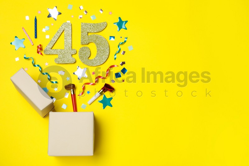 Flat lay composition with decor and numbers on yellow background, space for text. 45th birthday party