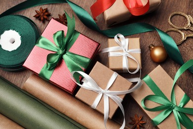 Photo of Flat lay composition with beautiful Christmas gift boxes and wrapping paper on wooden table