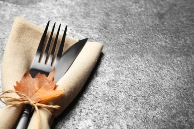 Cutlery and autumn leaf on grey background, closeup with space for text. Thanksgiving Day celebration