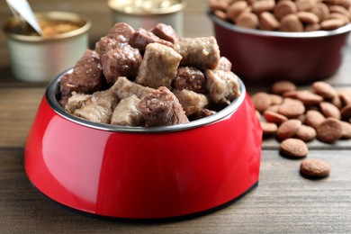 Wet pet food in feeding bowl on wooden table, closeup