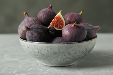 Tasty raw figs in bowl on light grey marble table, closeup