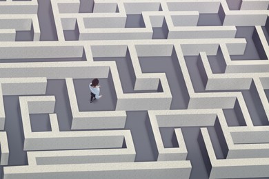 Image of Businesswoman trying to find way out of maze, above view