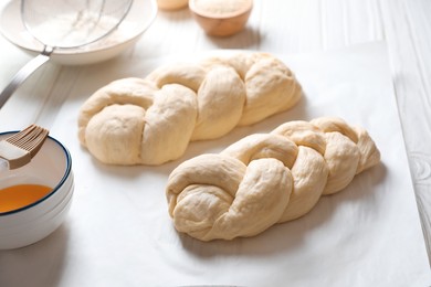 Photo of Homemade braided breads and ingredients on white wooden table, above view. Cooking traditional Shabbat challah