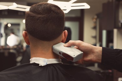 Professional hairdresser making stylish haircut in salon, back view