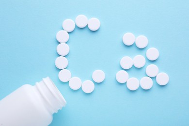 Open bottle and calcium symbol made of white pills on light blue background, flat lay