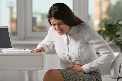 Young woman suffering from menstrual pain in office