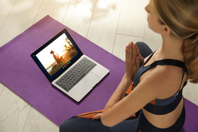 Image of Distance yoga course during coronavirus pandemic. Woman having online practice with instructor via laptop at home