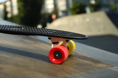 Modern black skateboard with colorful wheels on ramp outdoors, closeup