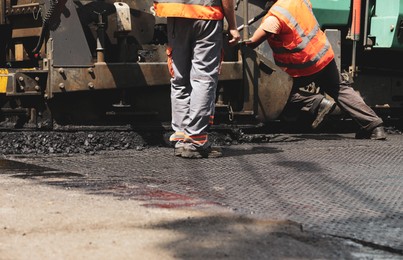 Workers laying new asphalt with paver, closeup. Road repair