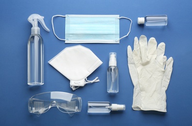 Flat lay composition with medical gloves, masks and hand sanitizer on blue background
