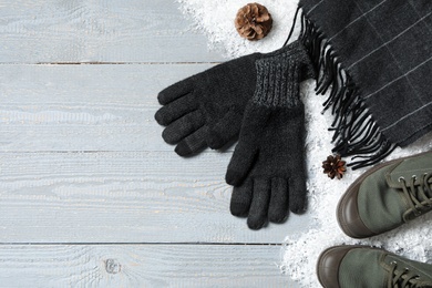 Stylish woolen gloves, scarf, pair of shoes and winter decor on grey wooden table, flat lay. Space for text