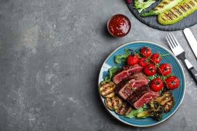 Delicious sliced beef steak served on grey table, flat lay. Space for text