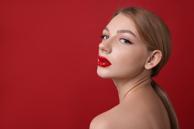 Photo of Beautiful young woman with perfect makeup on red background. Space for text
