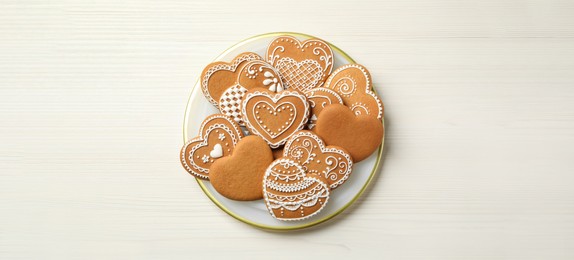 Image of Tasty heart shaped gingerbread cookies on white wooden table, top view. Banner design