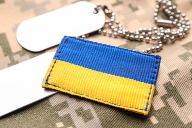 Military ID tags and patch on pixel Ukrainian camouflage, closeup