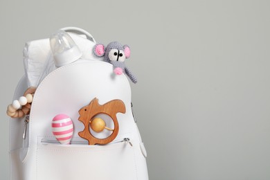 Photo of Mother's backpack with baby's stuff on light grey background. Space for text